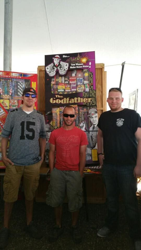 Three men are standing in front of a godfather poster.