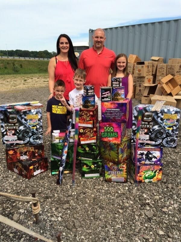 A family standing in front of a pile of fireworks