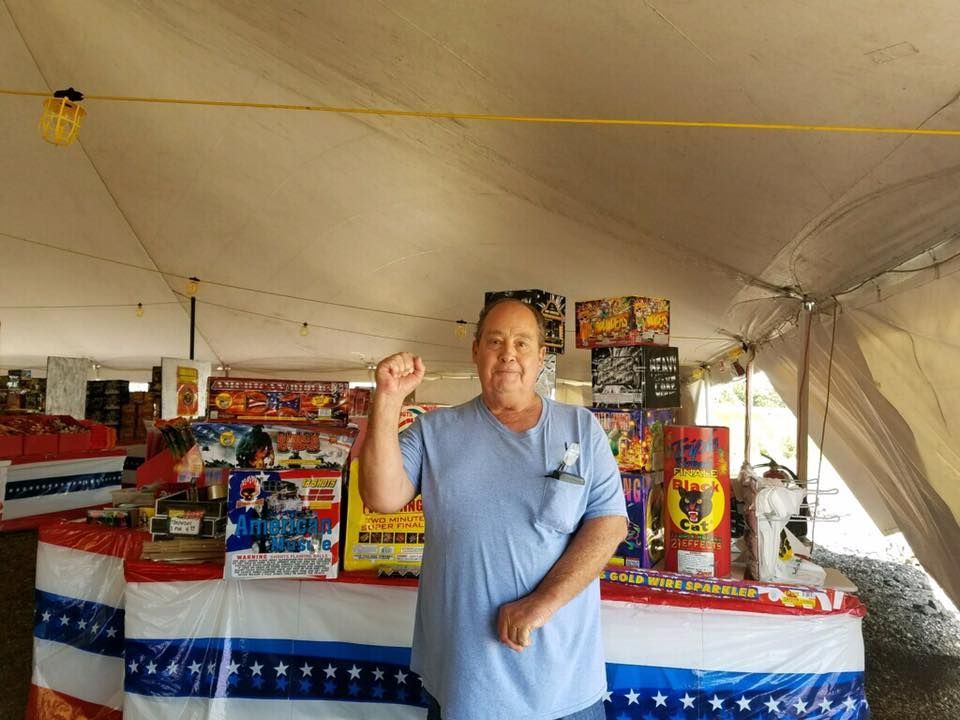 A man is standing in front of a table with fireworks on it.