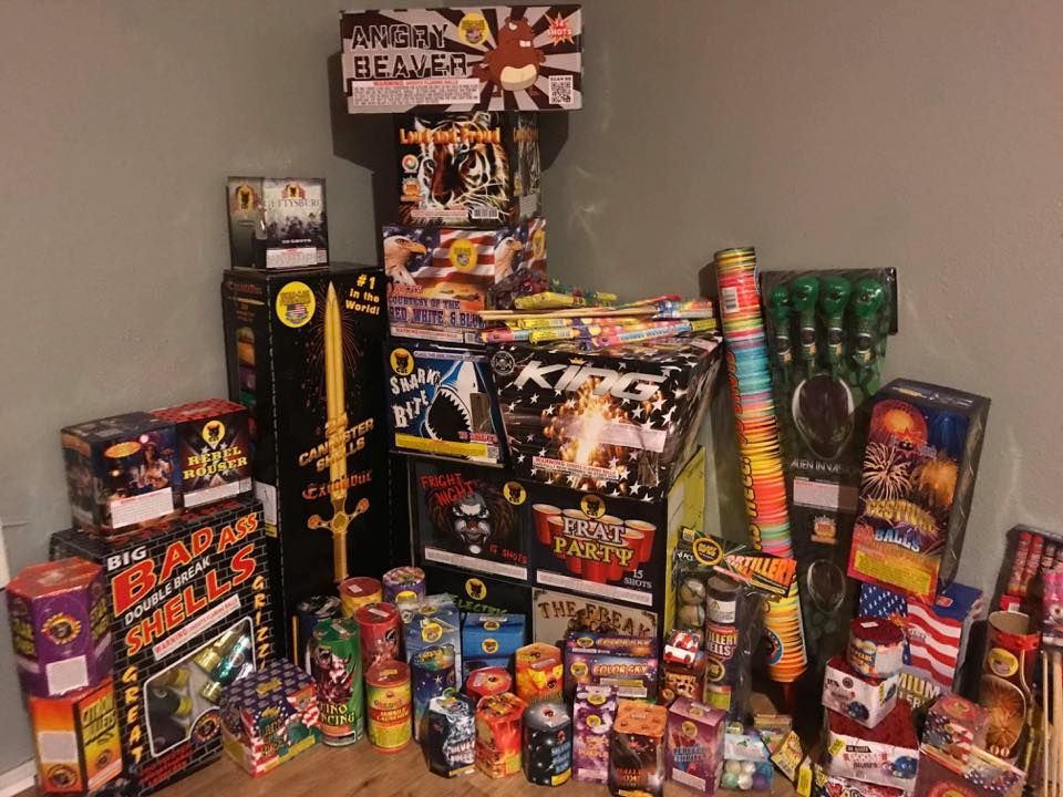 A bunch of fireworks are stacked on top of each other on a wooden floor.