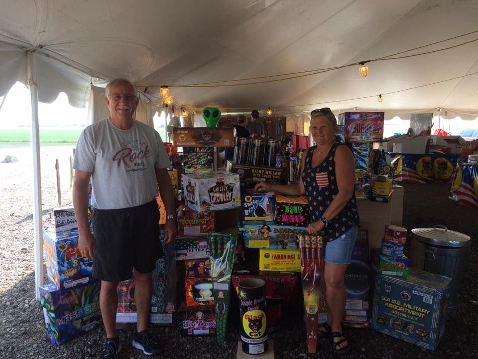 A man and a woman are standing in front of a tent filled with fireworks.