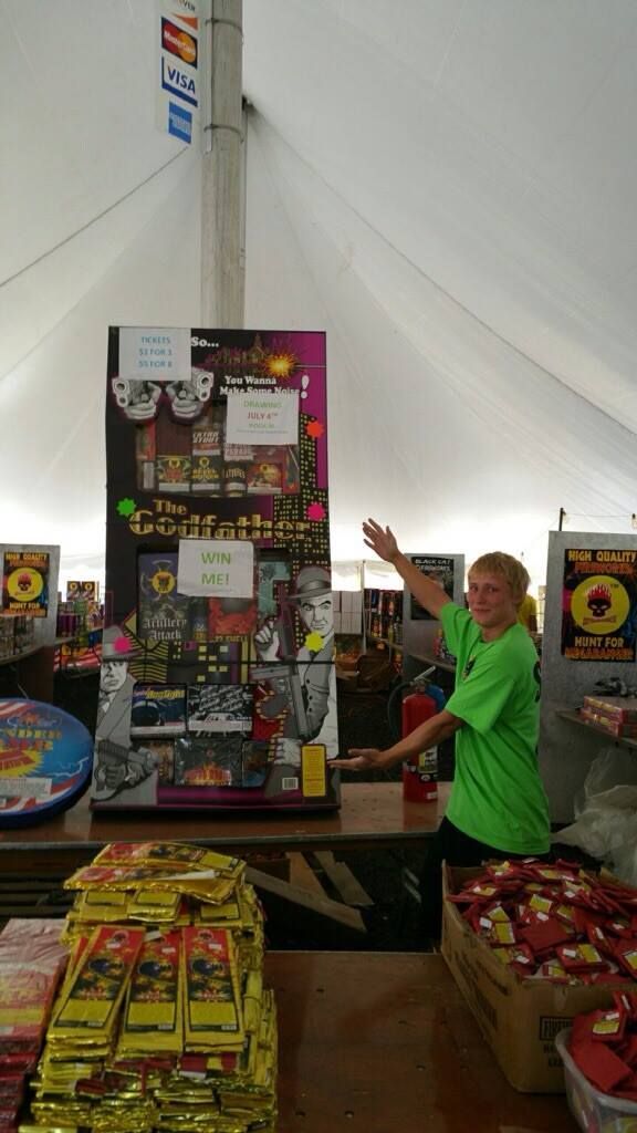 A man in a green shirt is standing behind a counter in a tent.