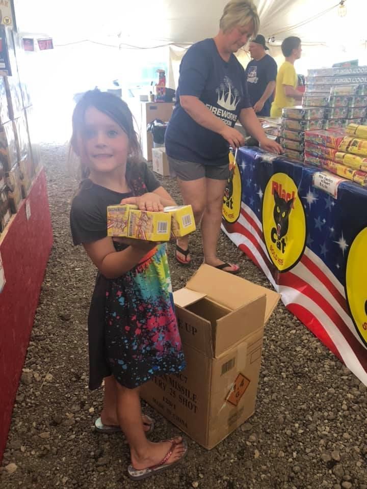 A little girl is standing next to a cardboard box