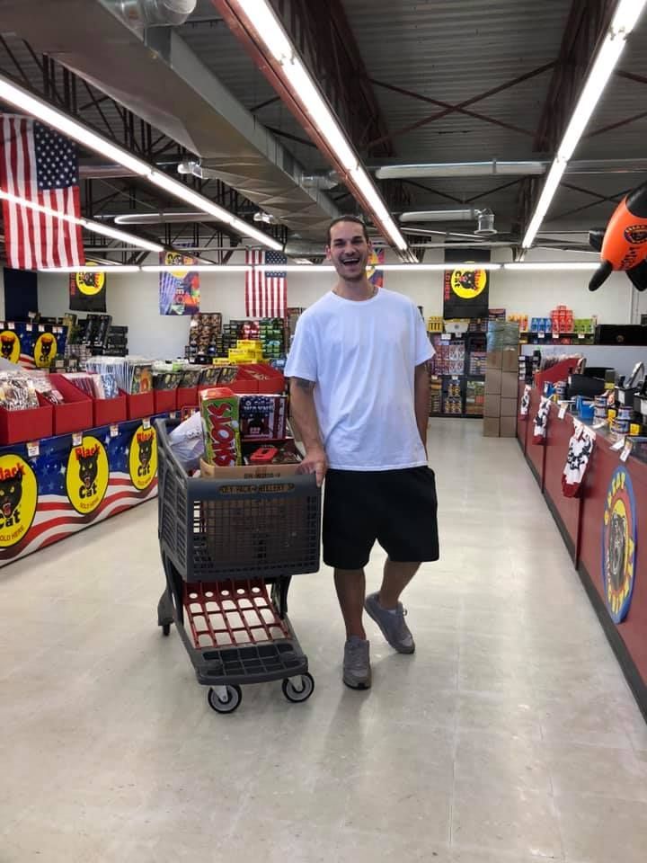 A man is standing next to a shopping cart in a store.