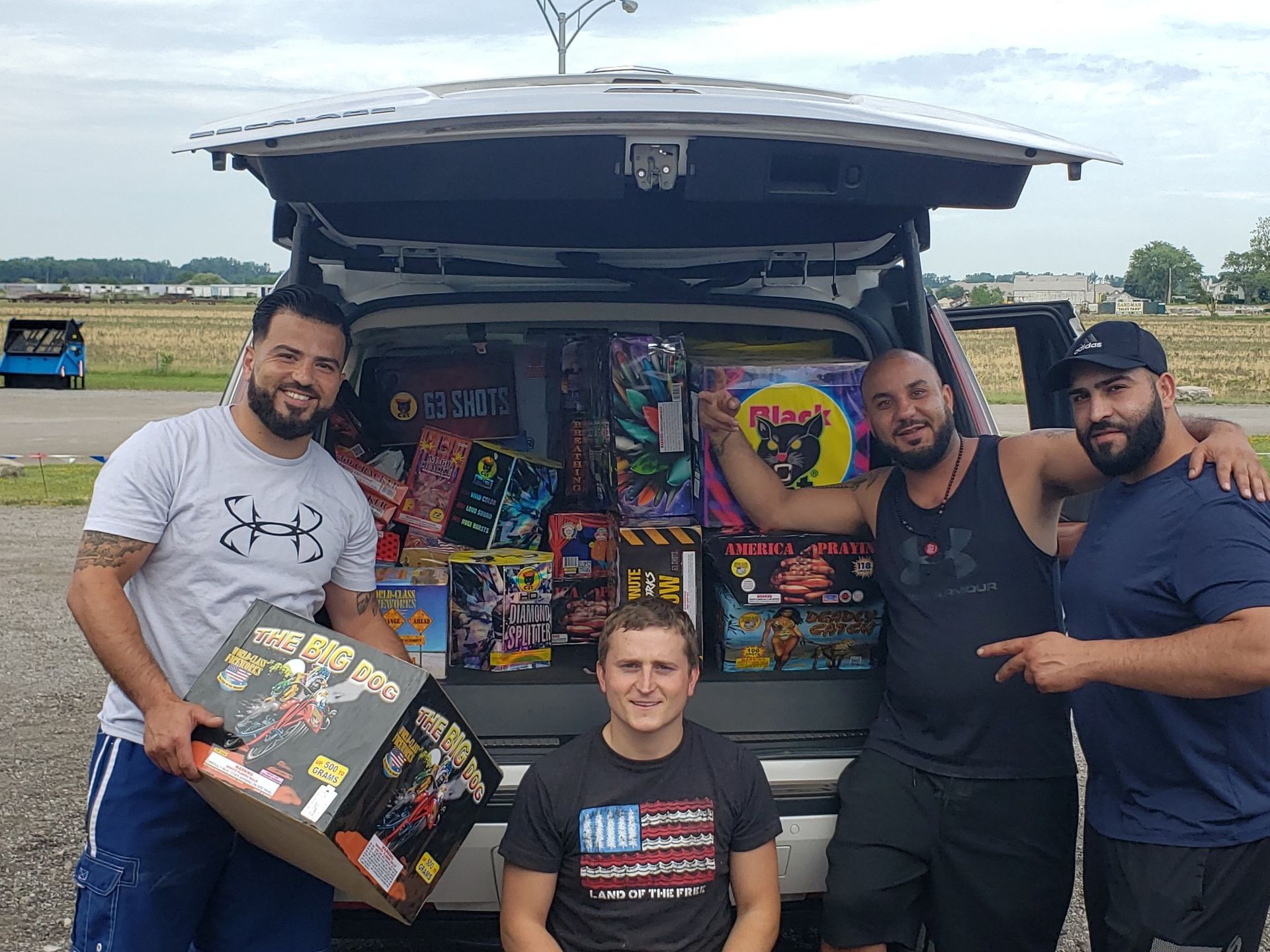 A group of men are standing in front of a van filled with fireworks.