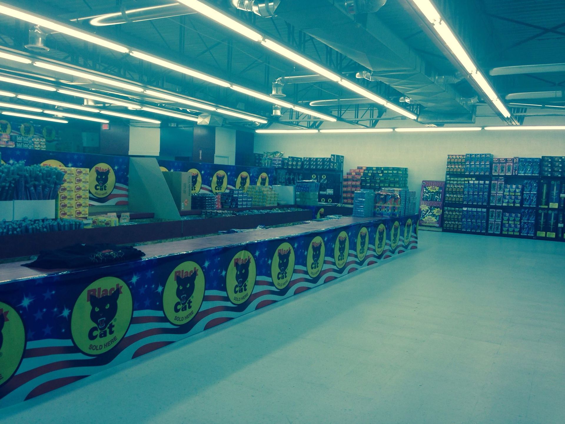 The inside of a store with a long counter with a cat on it.