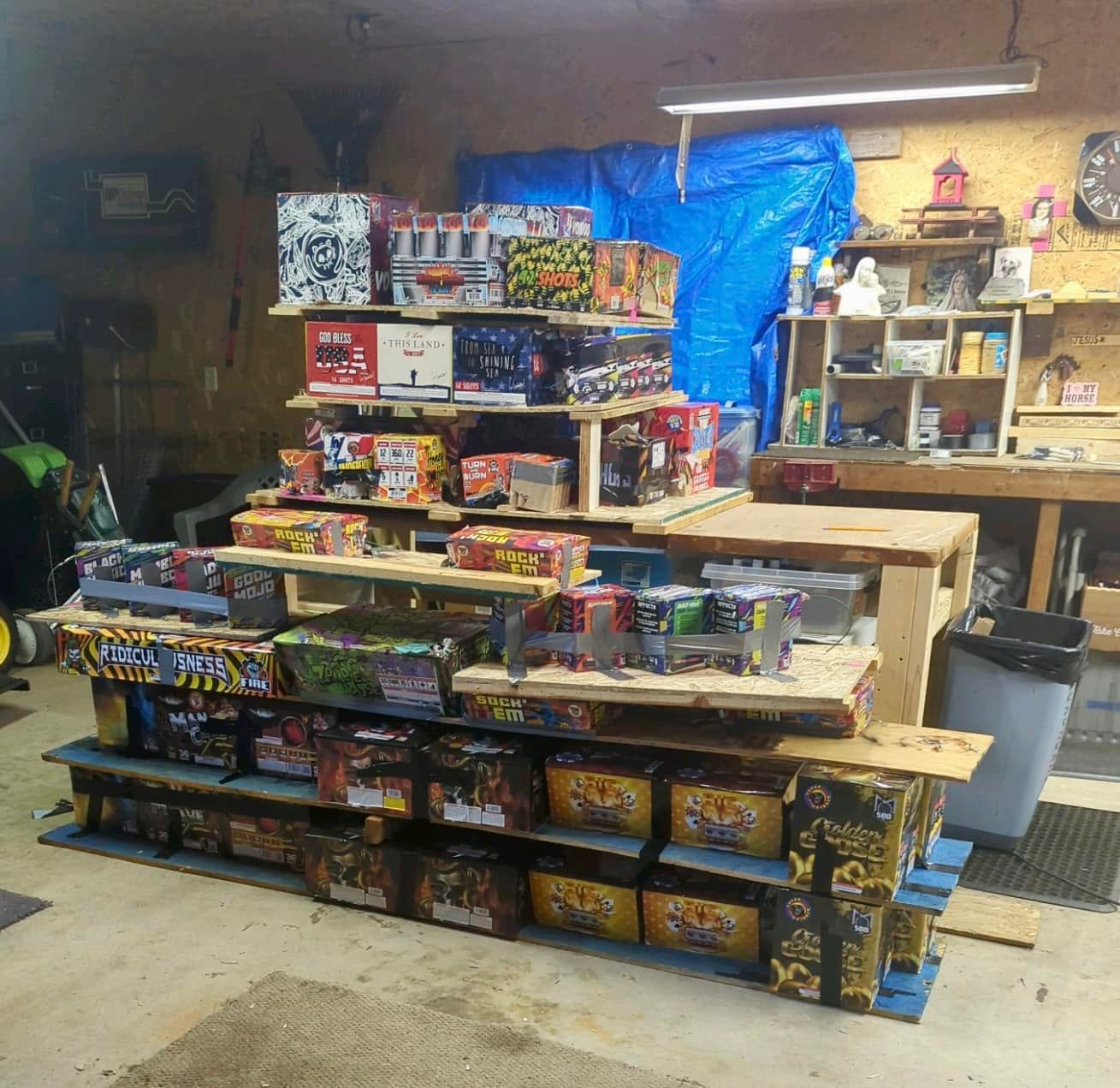 A bunch of fireworks are stacked on shelves in a garage