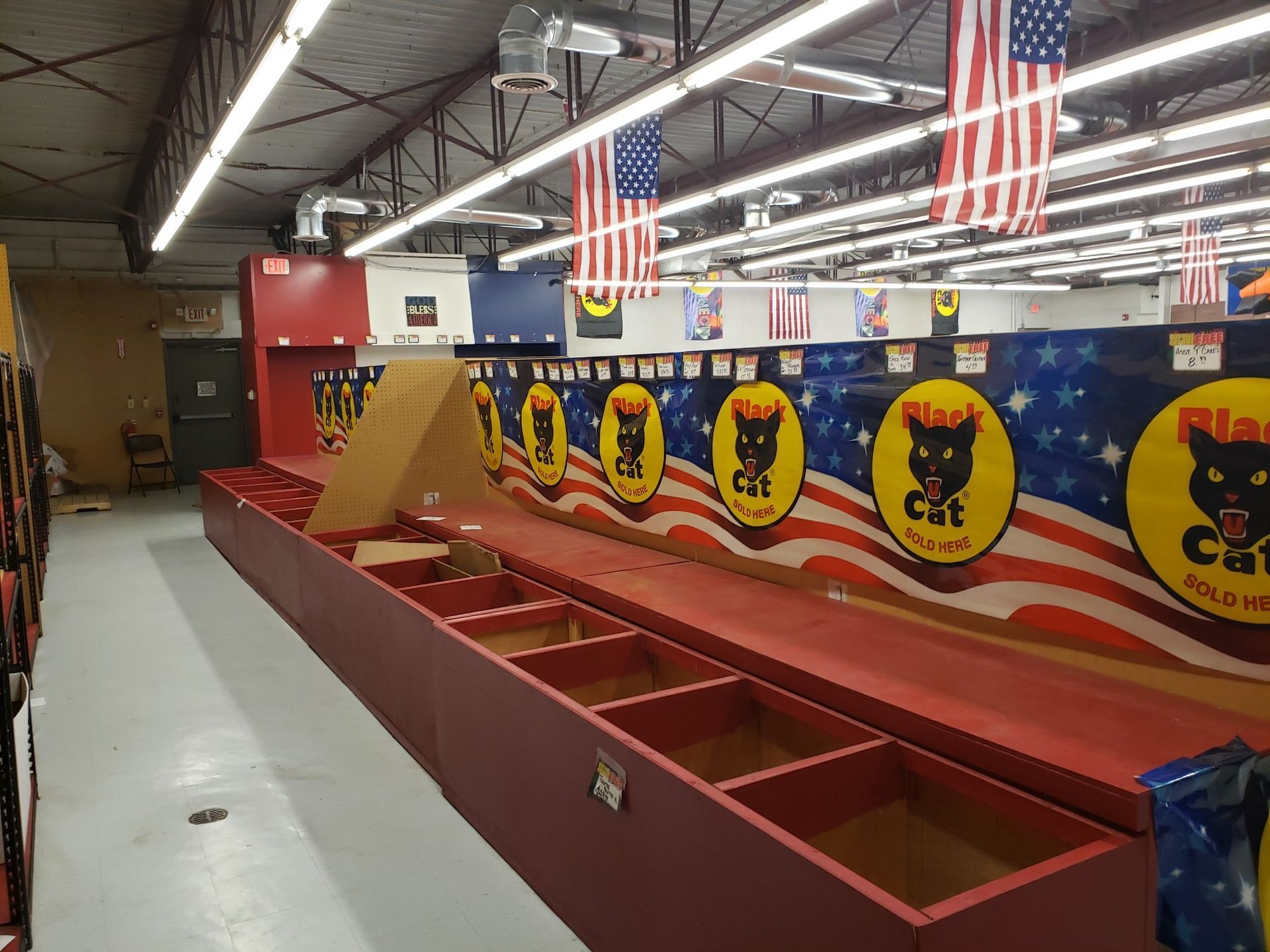 A large empty room with a lot of boxes and american flags hanging from the ceiling.