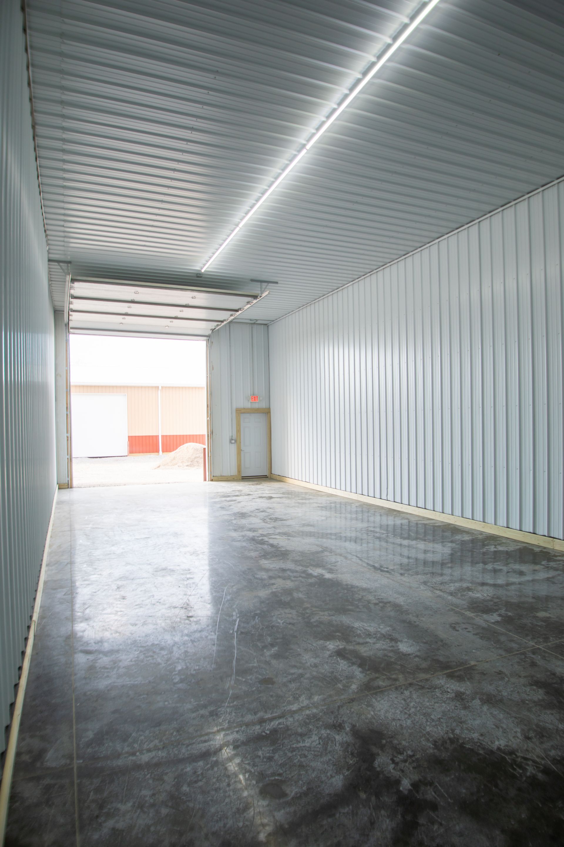 Worker in safety vest operates pallet jack near stacked boxes in shipping container.