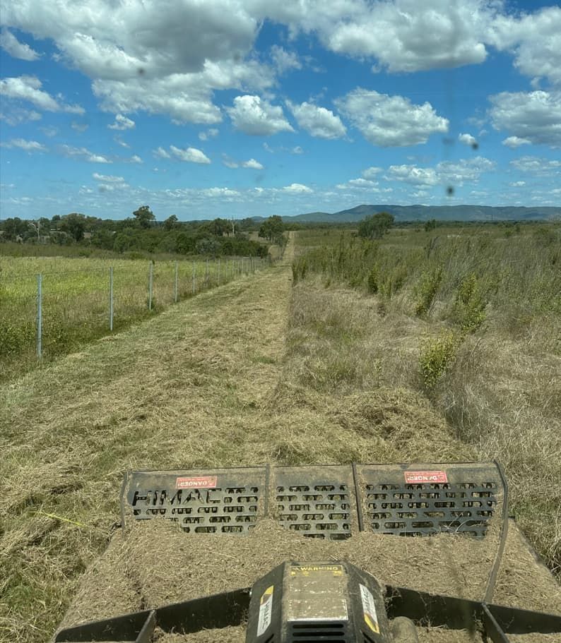 A Tractor Is Driving Down A Dirt Road In A Field — AMW Contracting Co In Cobraball, QLD