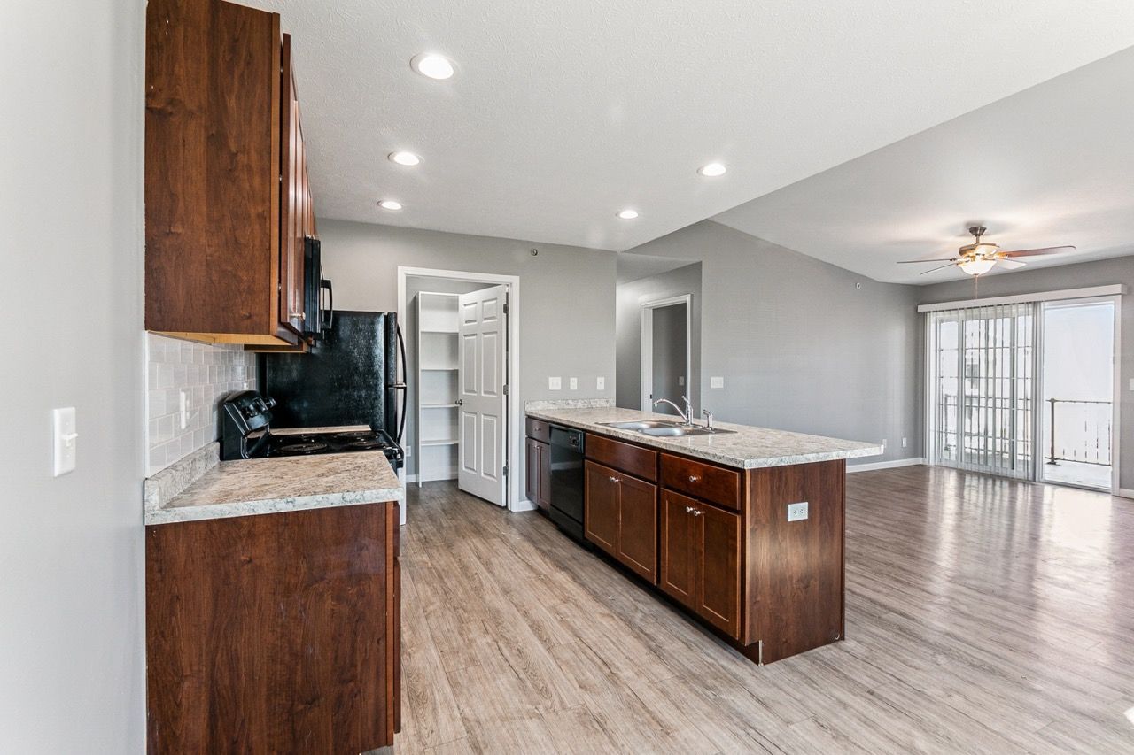 Kitchen with dark wood cabinets, island, and appliances; light countertops and flooring; gray walls.