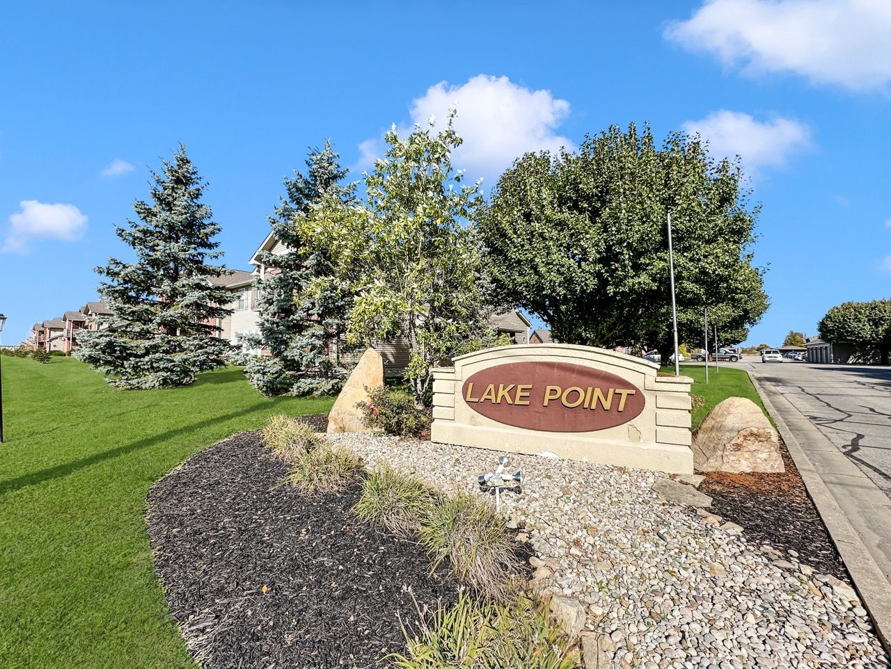 Sign for Lake Point with brown lettering and decorative rocks and landscaping.