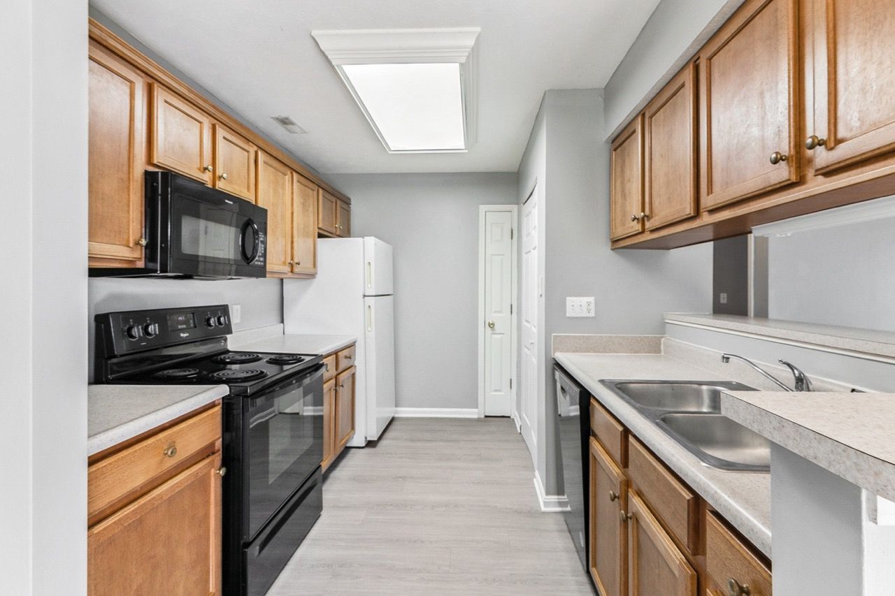 Kitchen with light wood cabinets, gray walls, and black appliances.