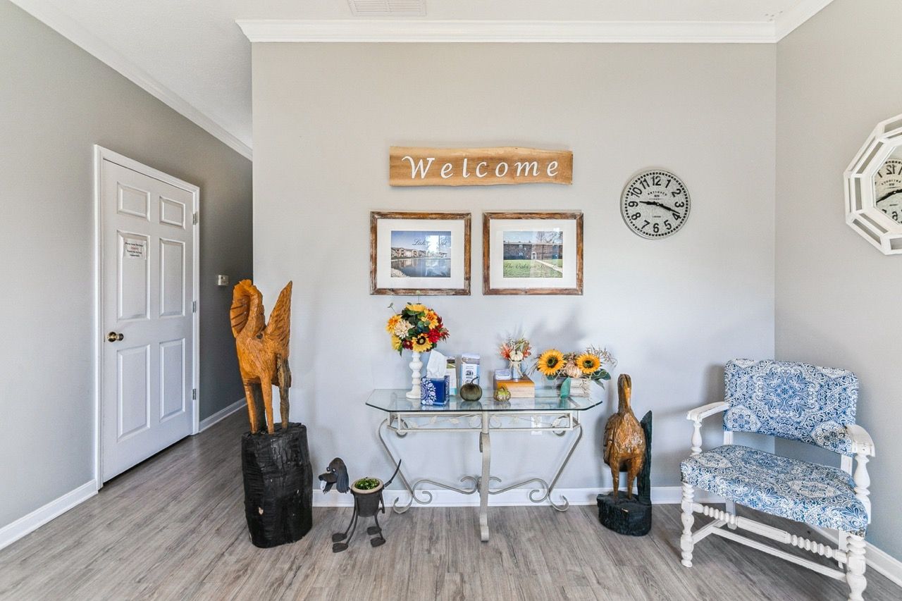 Entryway with light grey walls, decor, table, and a blue and white patterned chair.