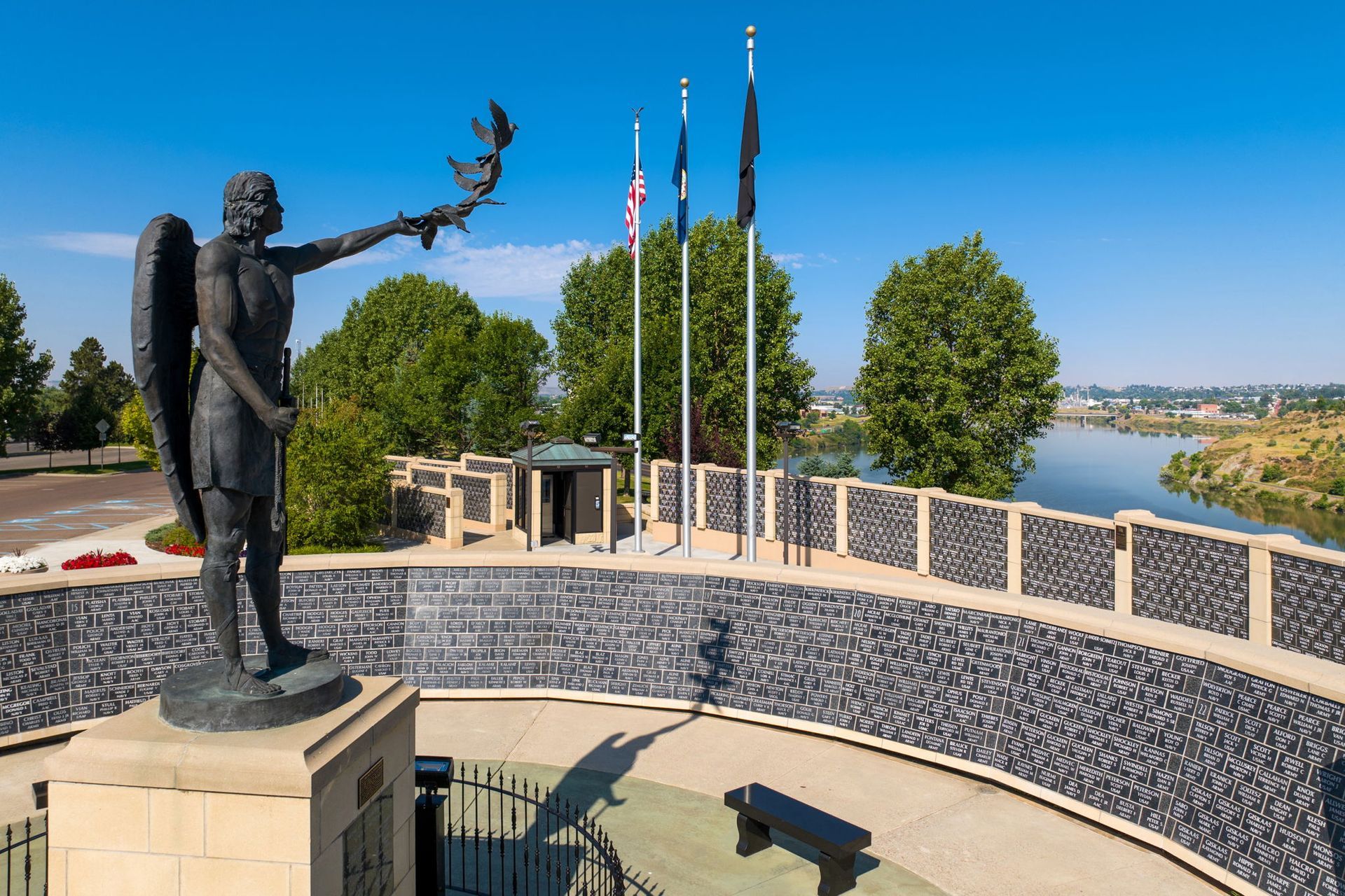 A statue of an angel holding a dove in front of a river.