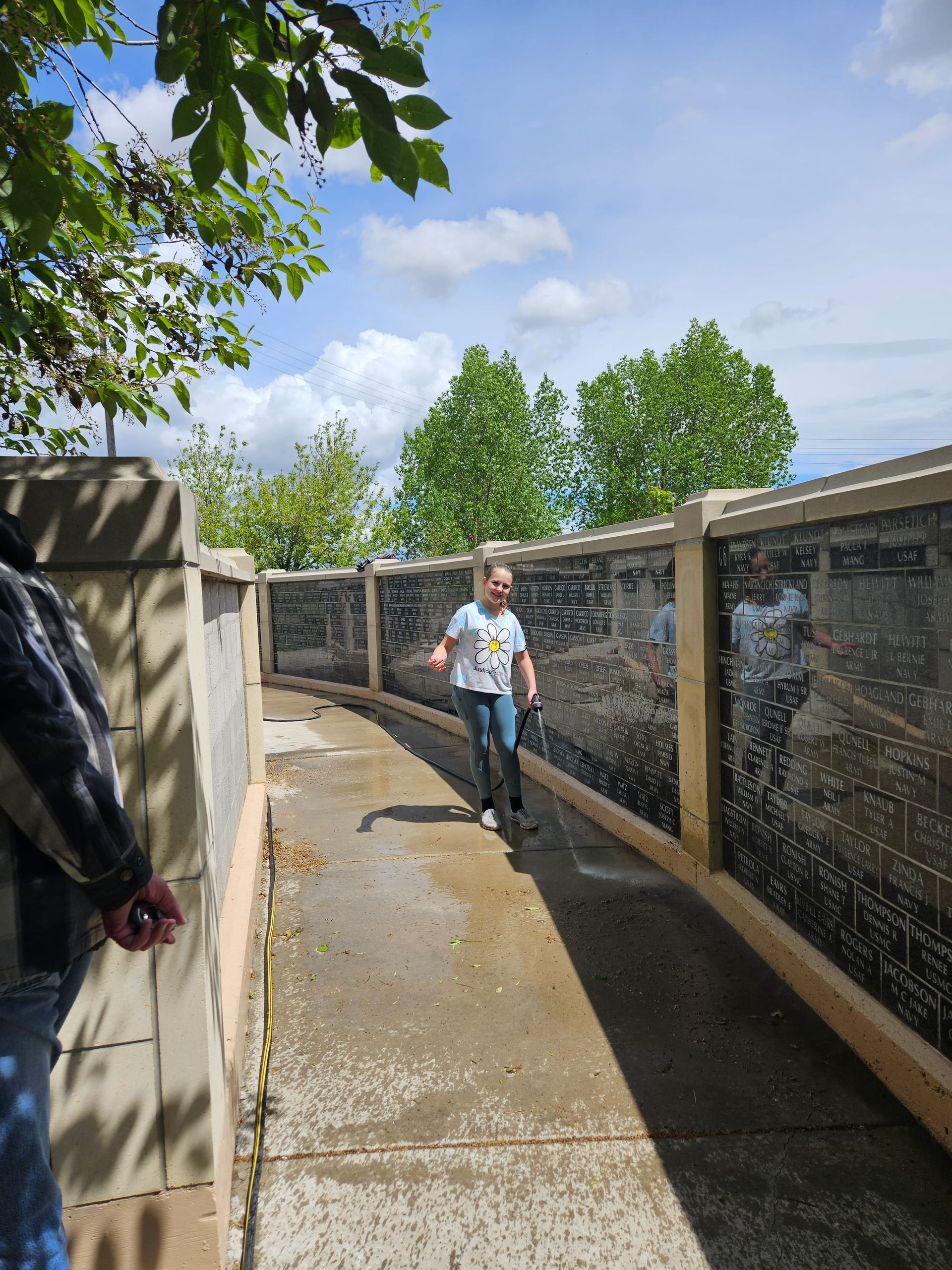 A person walking down a sidewalk next to a fence