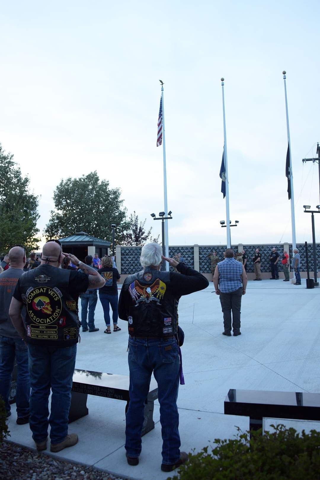A group of people are standing in front of a flag pole.