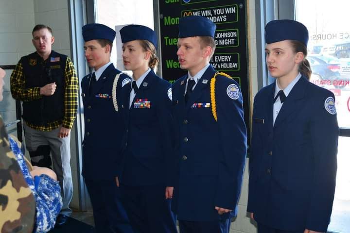 A group of people in military uniforms are standing in front of a sign that says 