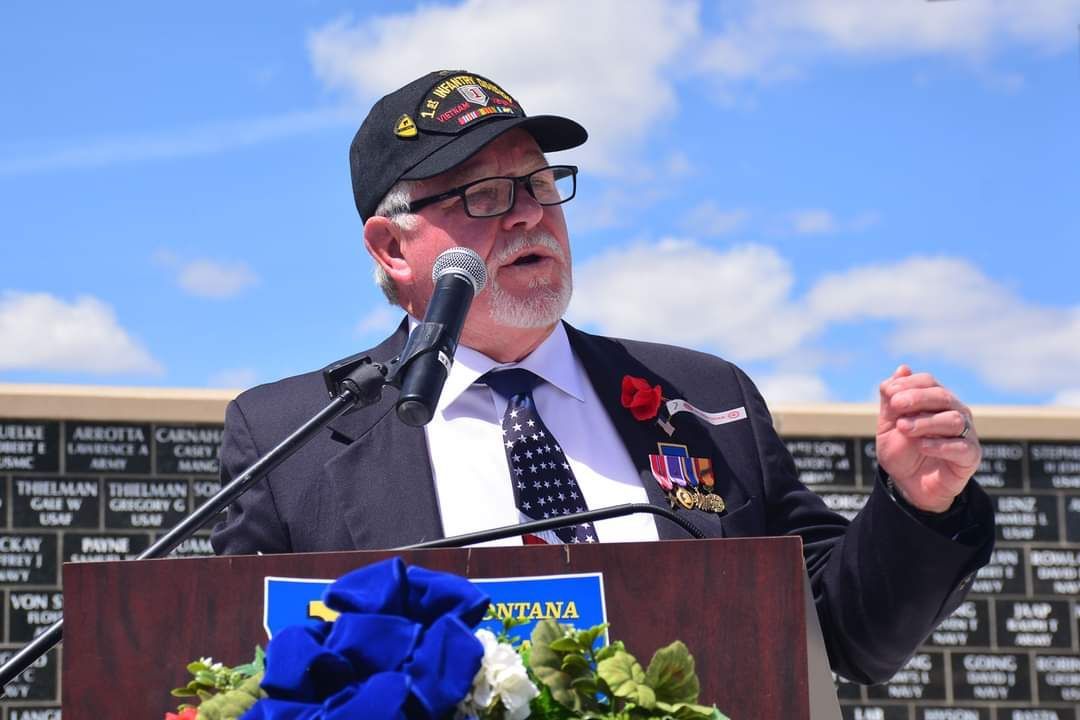 A man in a suit and tie is speaking into a microphone