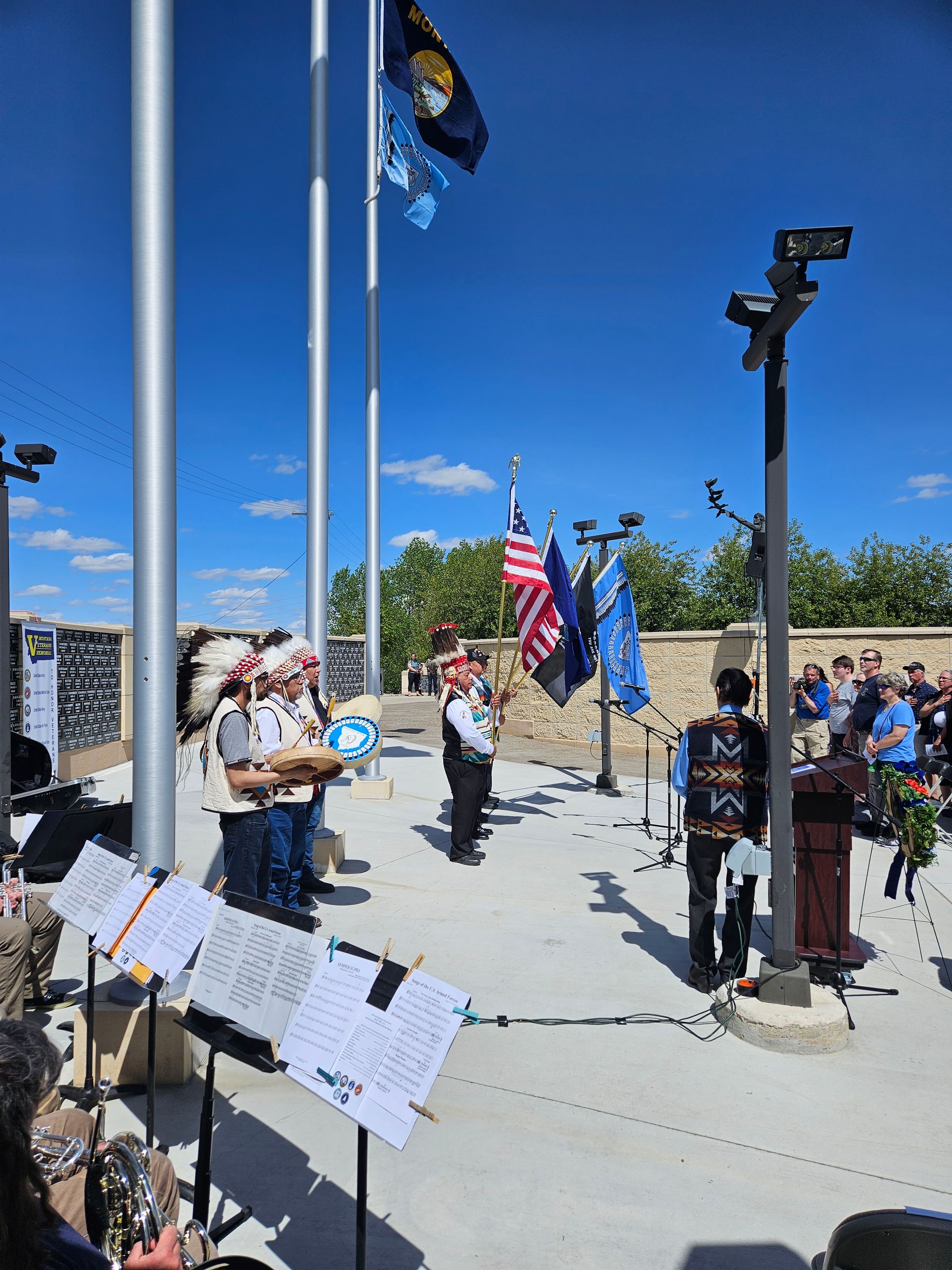 A group of people are standing in front of a flag pole.