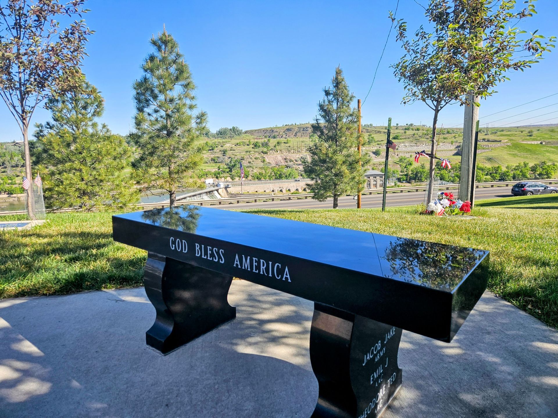 A black bench in a park that says god bless america
