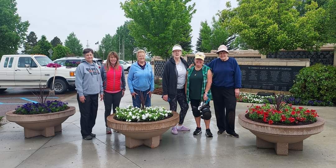 A group of people are standing next to planters of flowers.