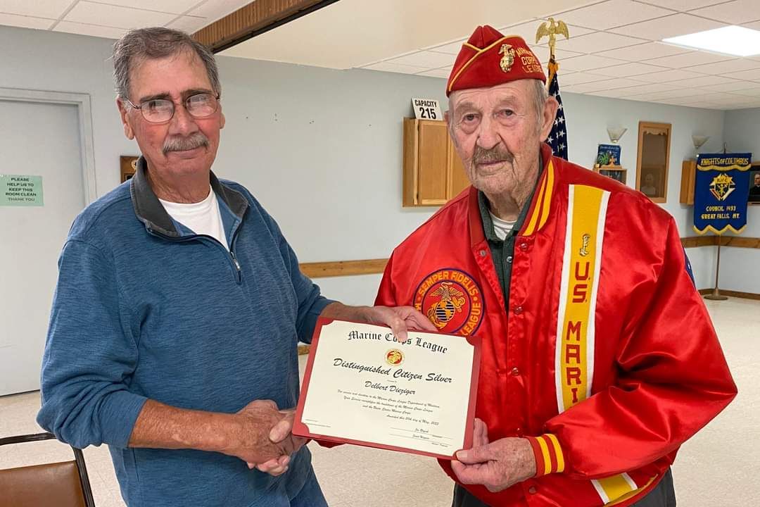 A man in a red jacket is shaking hands with another man