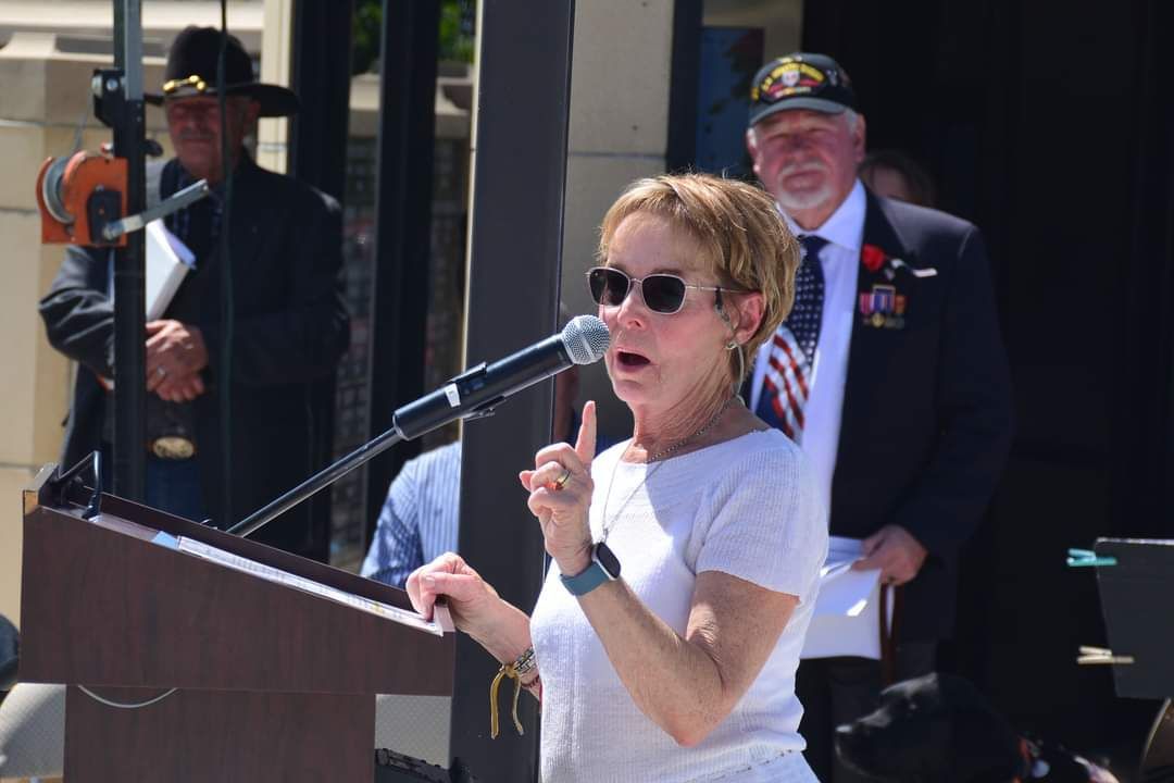 A woman is standing at a podium speaking into a microphone.