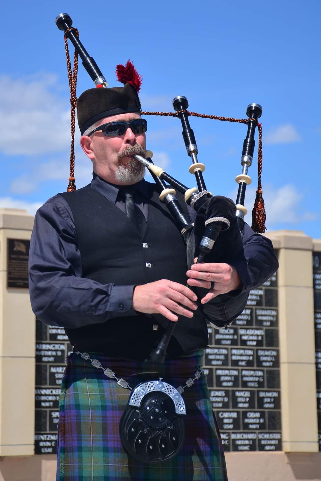 A man in a kilt is playing a bagpipe.