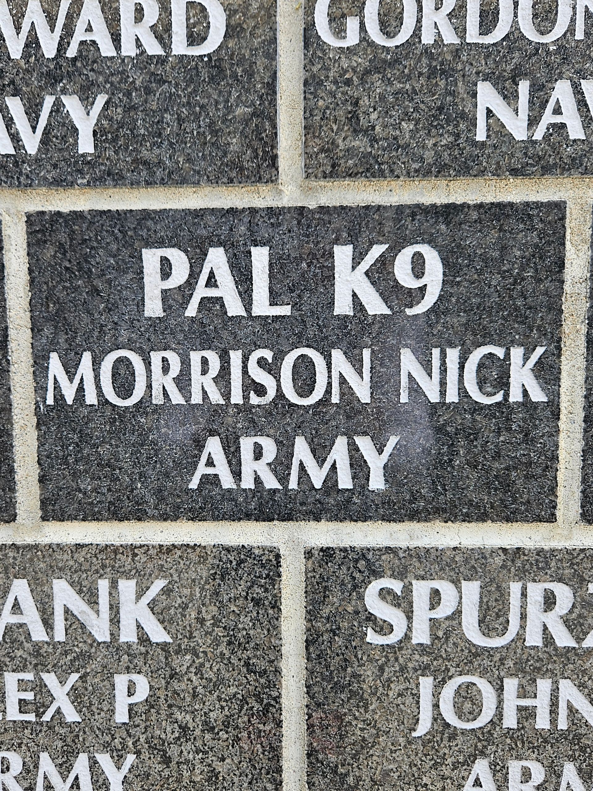 A brick wall with a plaque that says pal k9 morrison nick army