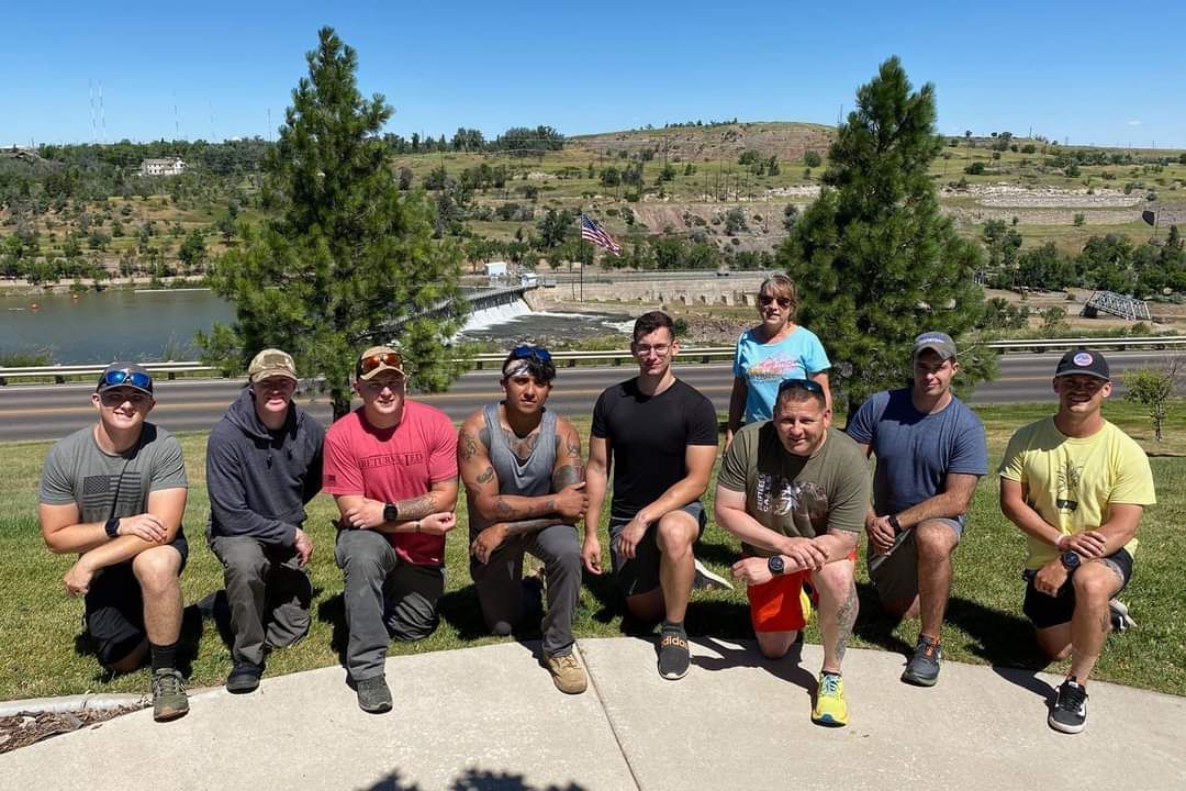 A group of people are posing for a picture in front of a lake.
