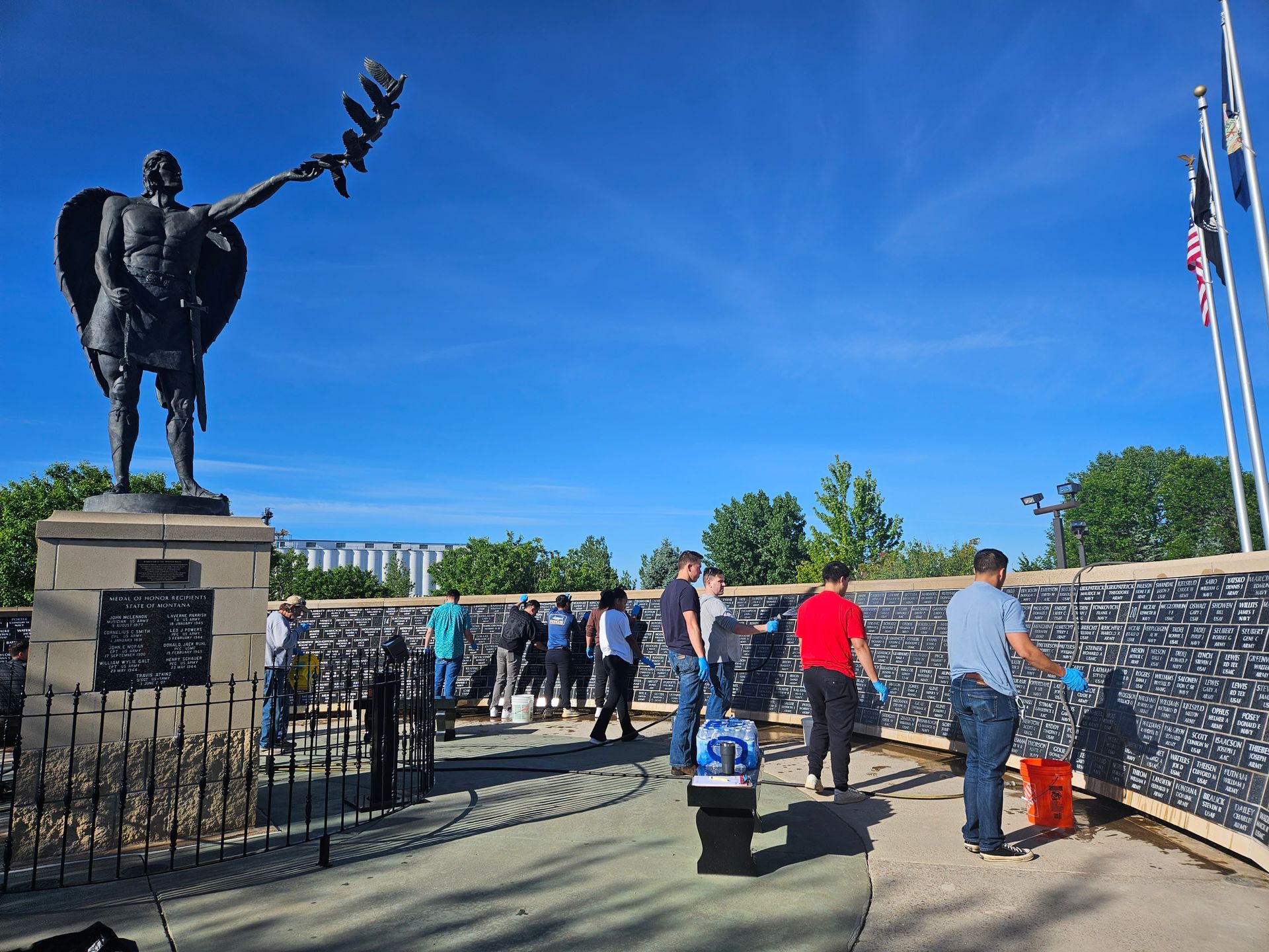 A group of people are standing in front of a statue of a man holding a bird.