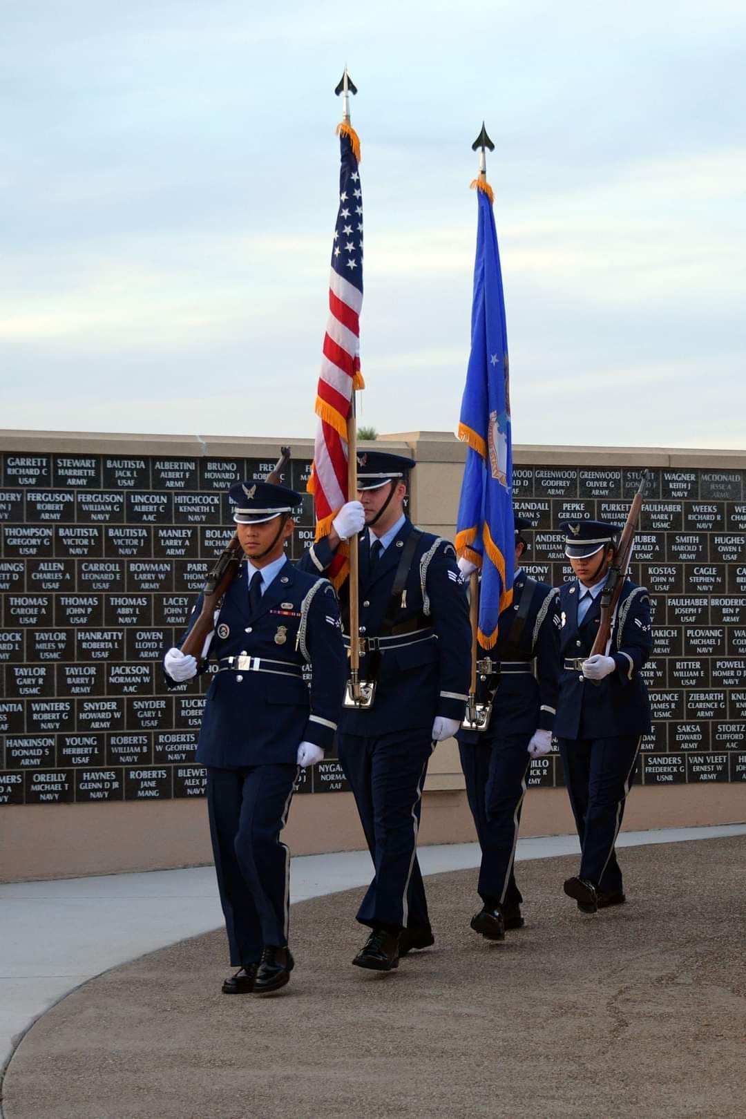 A group of soldiers marching with flags in front of a wall