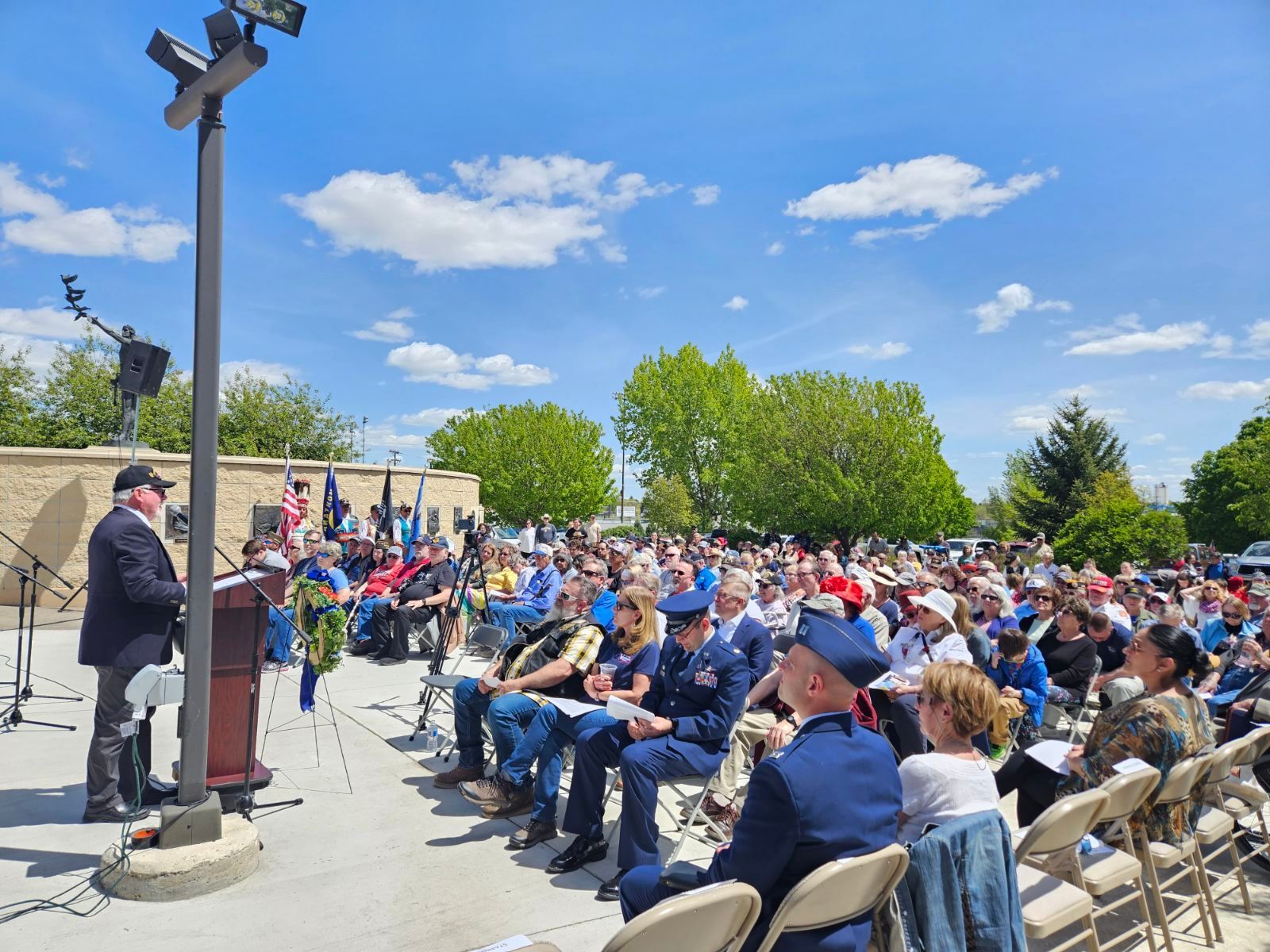 A man is giving a speech to a crowd of people sitting in chairs.