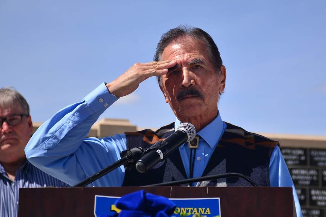 A man salutes while standing at a podium that says montana on it