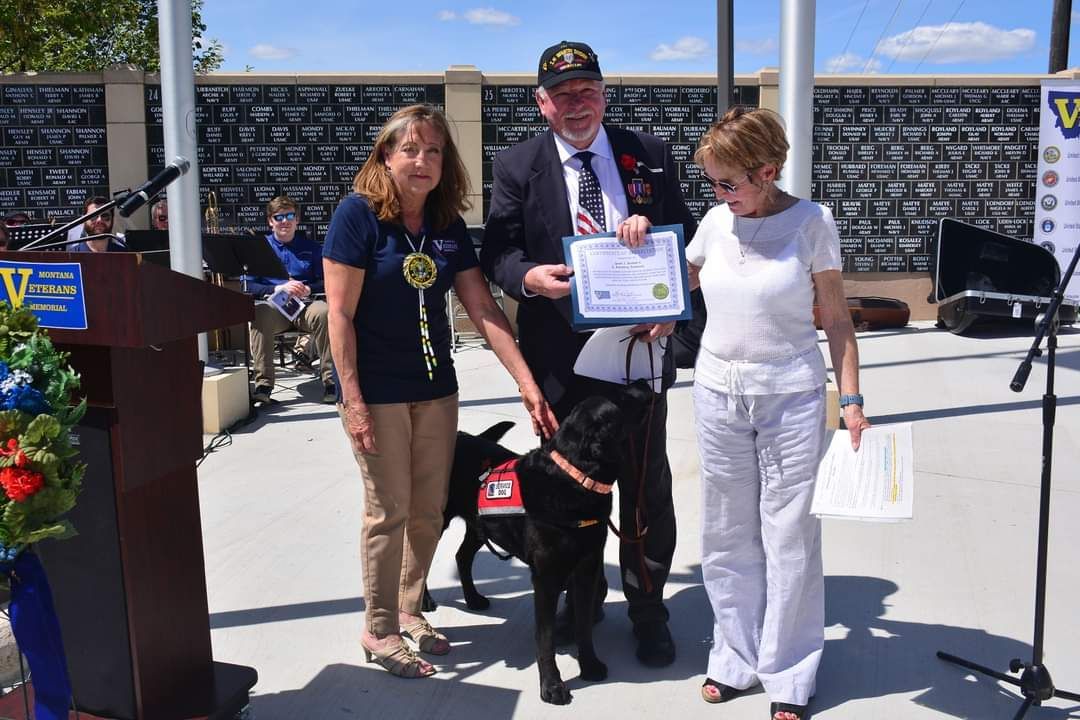 A group of people standing next to a dog holding a certificate.