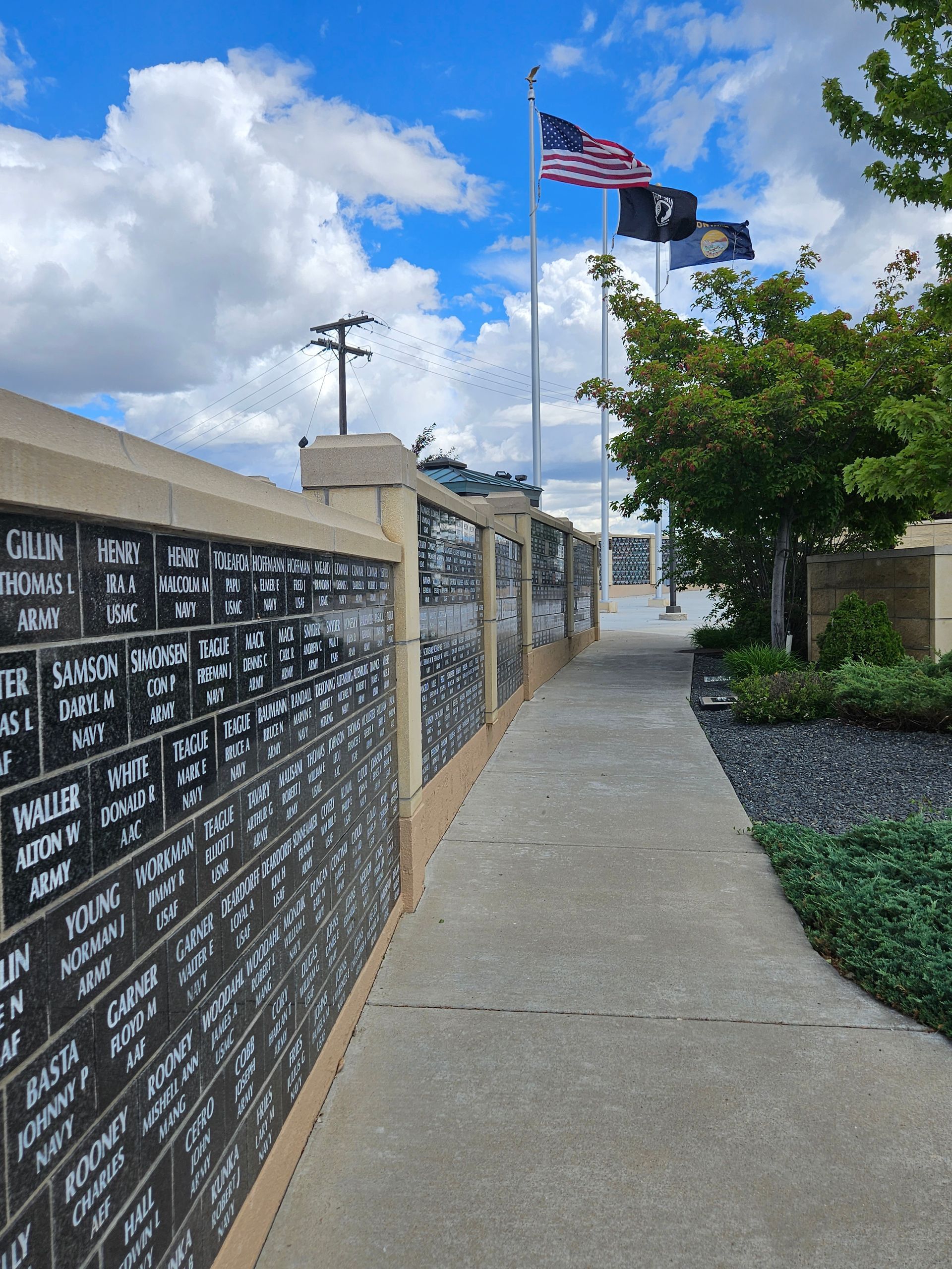 A sidewalk leading to a memorial with flags flying in the background.