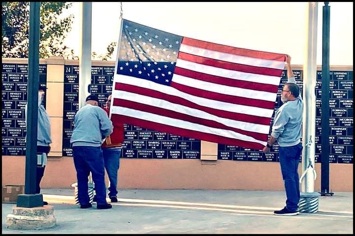 A group of men holding a large american flag