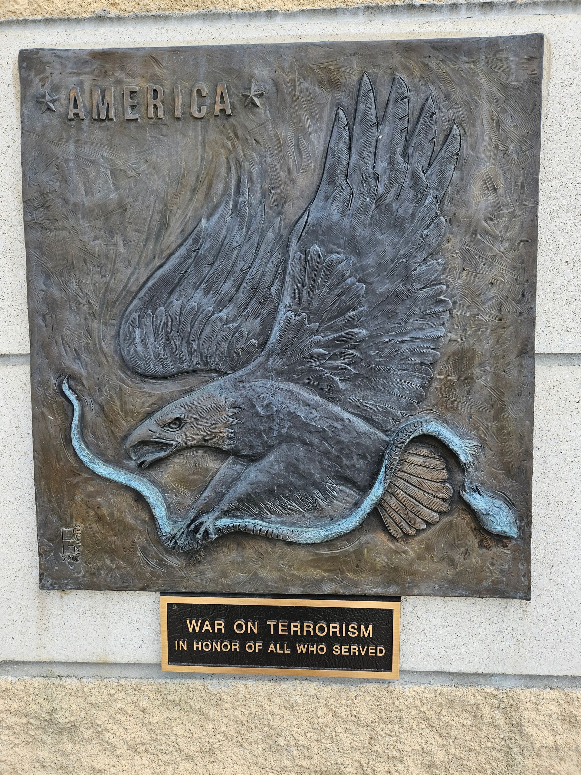 A statue of an eagle holding a snake on a wall.