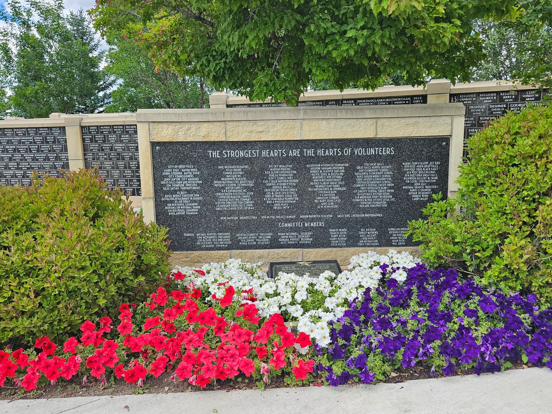 A memorial with red , white and purple flowers in front of it.