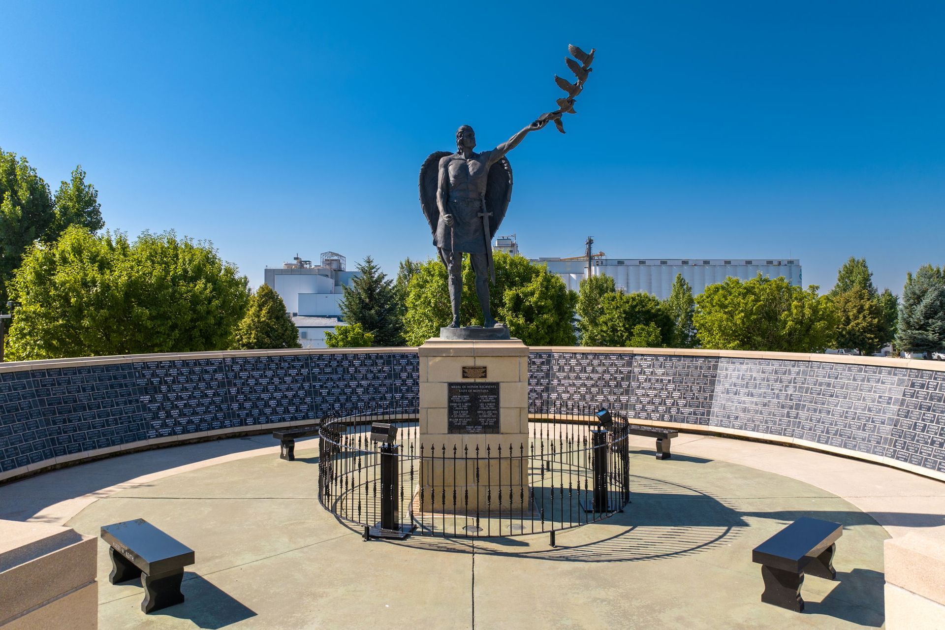 A statue of a man holding a flag in front of a wall of names.
