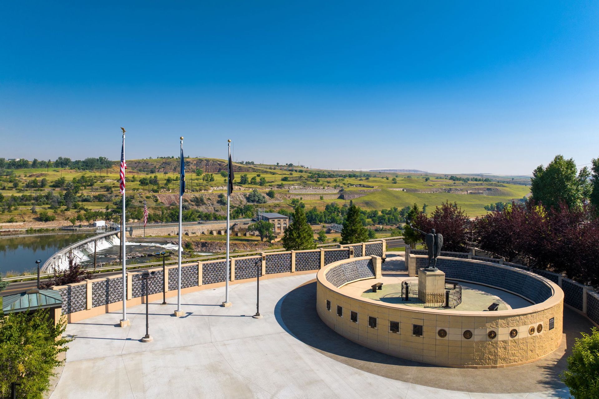 An aerial view of a memorial with flags and a lake in the background.