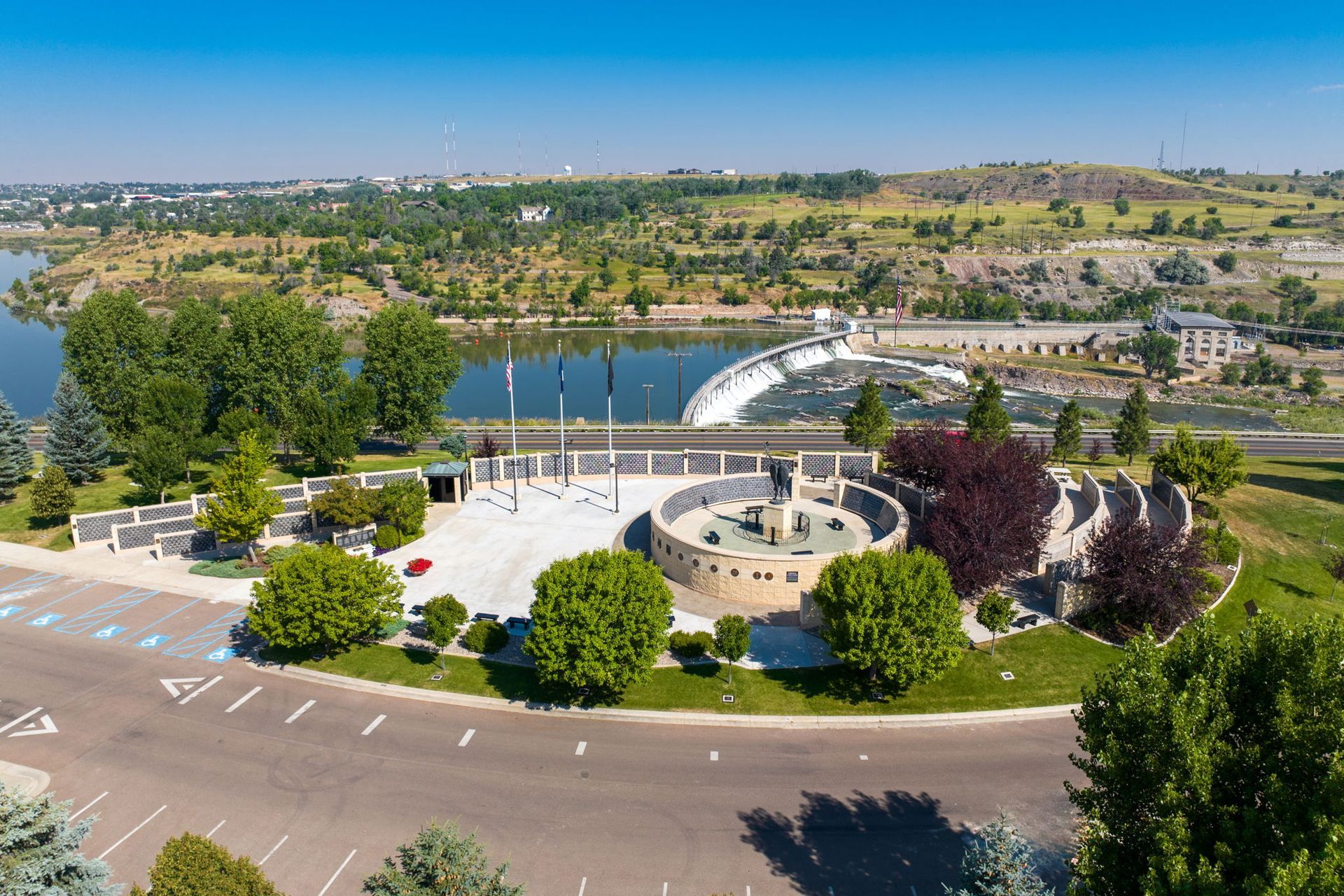 An aerial view of a park with a fountain and a lake in the background.