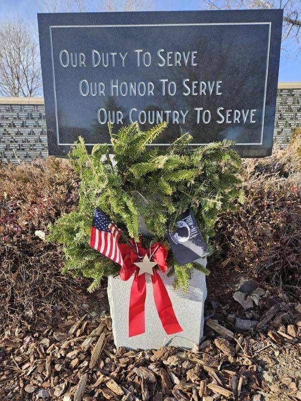 A wreath is sitting in front of a sign that says `` our duty to serve our honor to serve our country to serve ''.