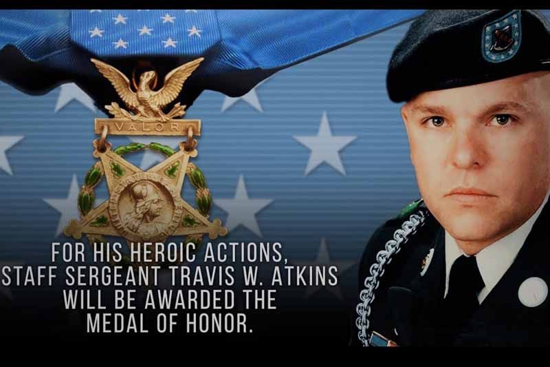 A man in a military uniform is standing in front of a medal of honor