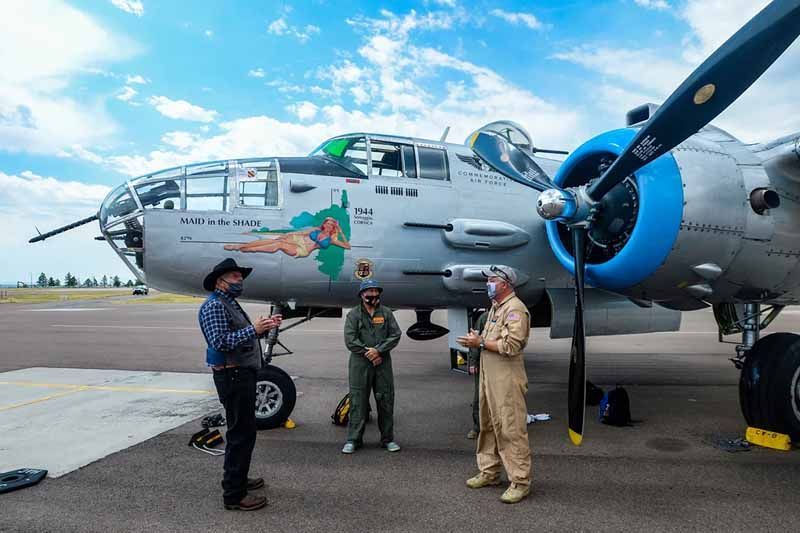 Three men are standing in front of a large airplane.