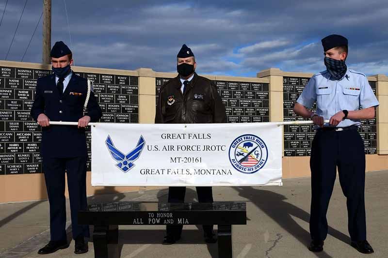 Three men in military uniforms holding a banner that says greatfalls us air force base