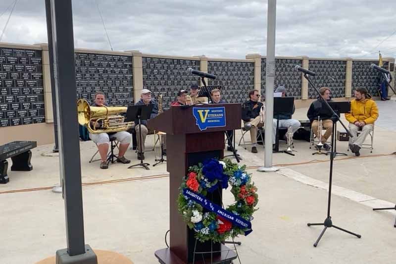 A group of people are sitting around a podium with a wreath on it.