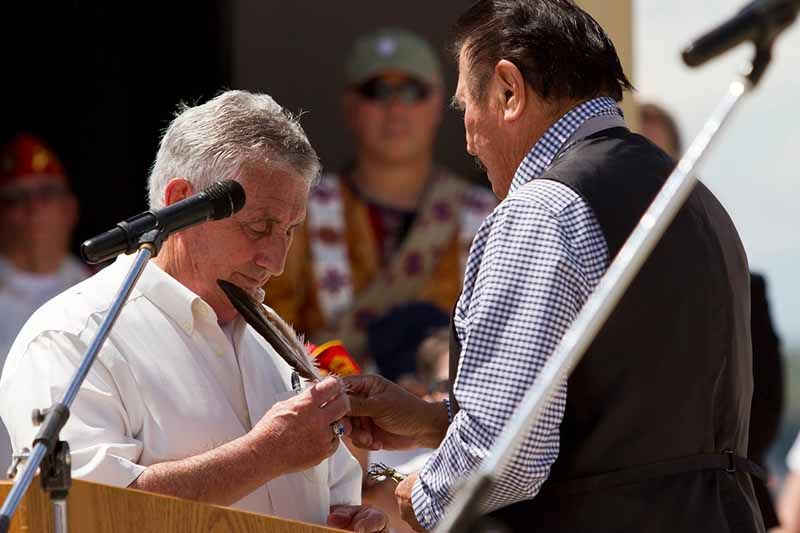 Two men are standing next to each other in front of a microphone.