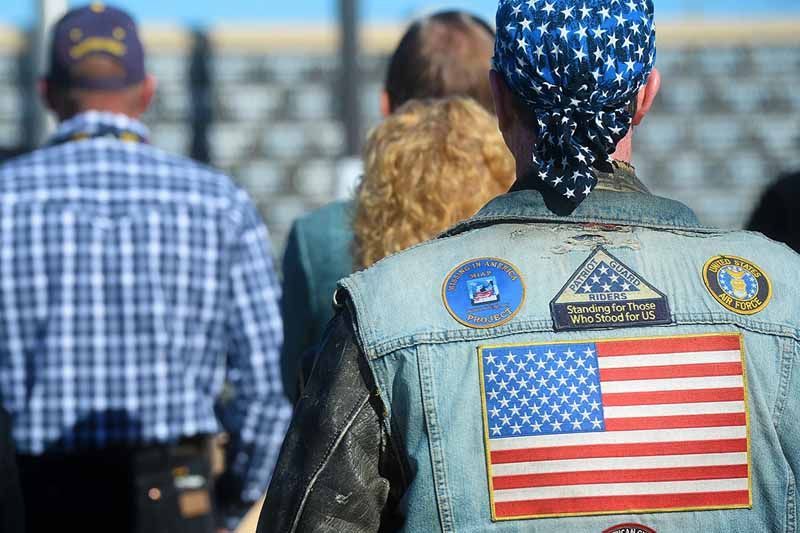 A man wearing a denim vest with an american flag on the back.